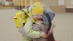 little girl schoolgirl with backpack runs hug her mother, kid rejoice over lessons, happy family, school bag behind back