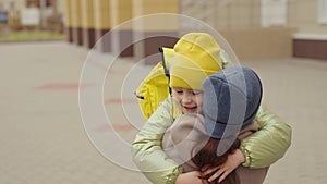 little girl schoolgirl with backpack runs hug her mother, kid rejoice over lessons, happy family, school bag behind back