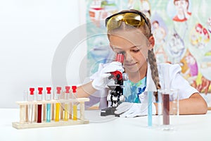 Little girl in science class using microscope