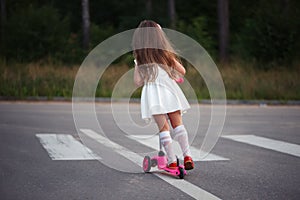 Little girl with scooter on the road