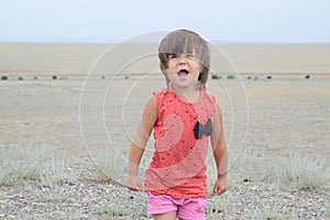 Little girl screaming in big landscape environment. Child emotionally saying loudly, singing a song with expression