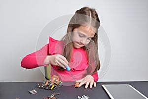 Little girl screws metal parts onto a robot. Concept of hands-on learning, education, creativity, and engineering exploration