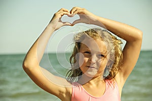Little girl on the sea hands on the heart