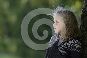 Little girl seated against a tree