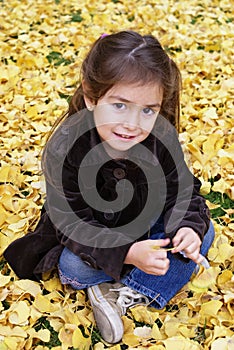 Little girl seating outdoor in autumn