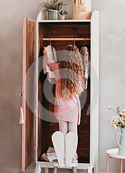 Little girl sews clothes in the closet