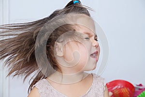 Little girl shakes head splashing hair. funny child with expressive emotion dancing