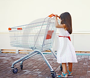 Little girl with shopping cart outdoors