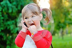 Little girl shouting into the phone in a park