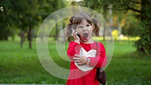 Little girl shouting into the phone in a park
