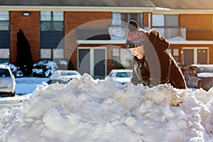 Little girl shoveling snow on home drive way. Beautiful snowy garden or front yard. Child with shovel playing outdoors in winter s