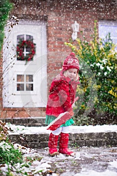 Little girl shoveling snow in winter