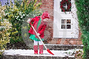 Little girl shoveling snow in winter