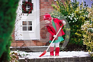 Little girl shoveling snow in winter