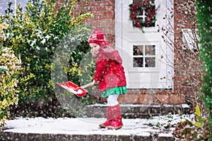 Little girl shoveling snow in winter