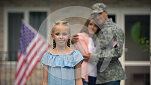 Little girl showing american flag strike in front of parents, patriots family