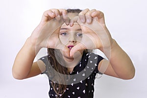 Little girl showing a drawing of a heart from folded hands ,close-up. Symbol of love, a heart made of children's hands