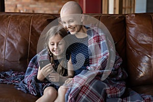 Little girl showing funny photo on cellphone to sick mother
