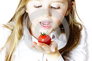 Little girl showing small red tomato