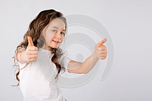 Little girl showing thumbs up gesture isolated on white background.