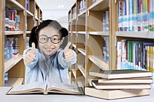 Little girl showing thumbs up in the library