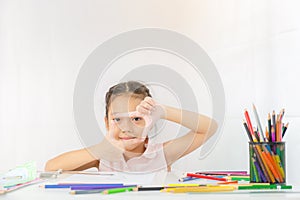 Little girl shows a frame from hands like photo, Kid drawing with colorful pencils