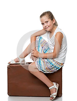 Little girl siiting on the suitcase