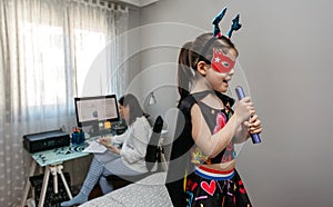 Girl singing in disguise while her mother teleworking photo