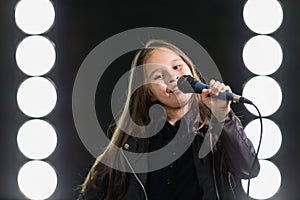 Little girl singing in front of stage lights