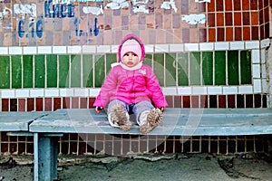 Little girl sit on bench on bus stop