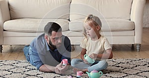 Little girl sit on carpet play tea party with dad