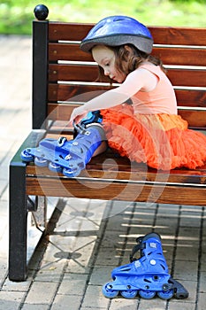 Little girl sits on bench and removes blue roller