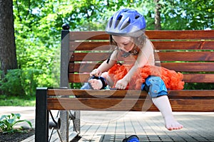 Little girl sits on bench and removes protective