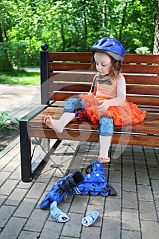 Little girl sits on bench and removes roller