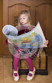 Little girl sits on a chest and considers world