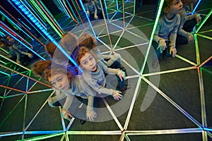 Little girl sits at crossing in mirror labyrinth