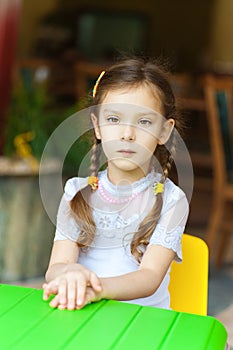 Little girl sits in at green table