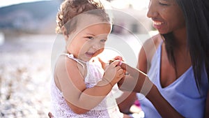 Little girl sits in her mother arms and tries to gnaw on a keychain with a key