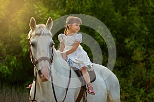 The little girl sits on a horse astride