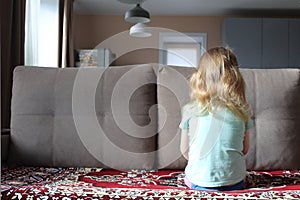 Little girl sits with an offended back on the couch