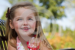 A little girl sits on a park bench