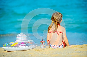 little girl sits on the seashore and looks out into the distance
