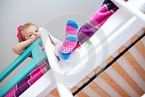 A little girl sits on the second floor of a bunk bed