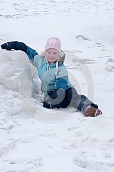 Little girl sits on snow