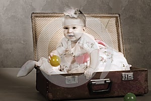 Little girl sits in a suitcase