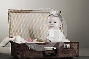 Little girl sits in a suitcase.