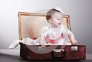 Little girl sits in a suitcase