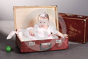 Little girl sits in a suitcase.