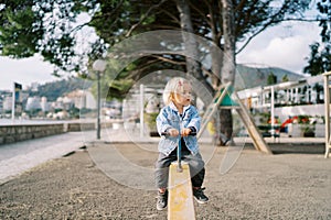 Little girl sits on a swing-balancer holding the handle