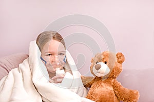 Little girl Sits with toy on sofa at home in a mask for inhalations, making inhalation with nebulizer at home inhaler